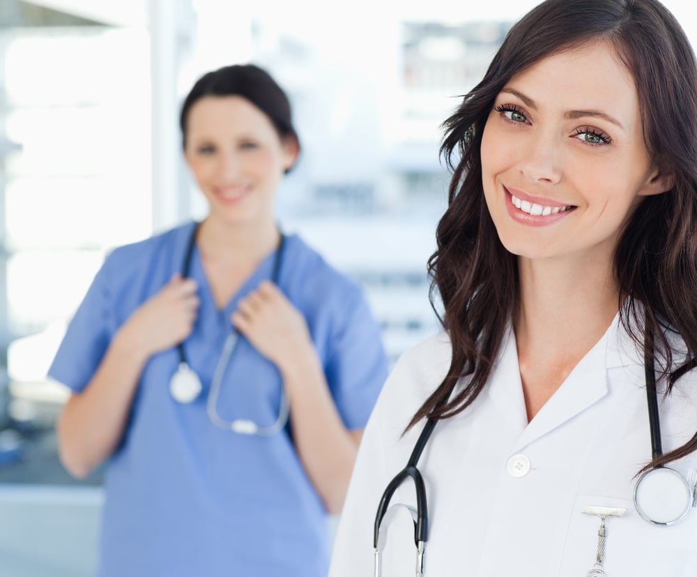 Young smiling nurse standing upright while leaning her head to the side
